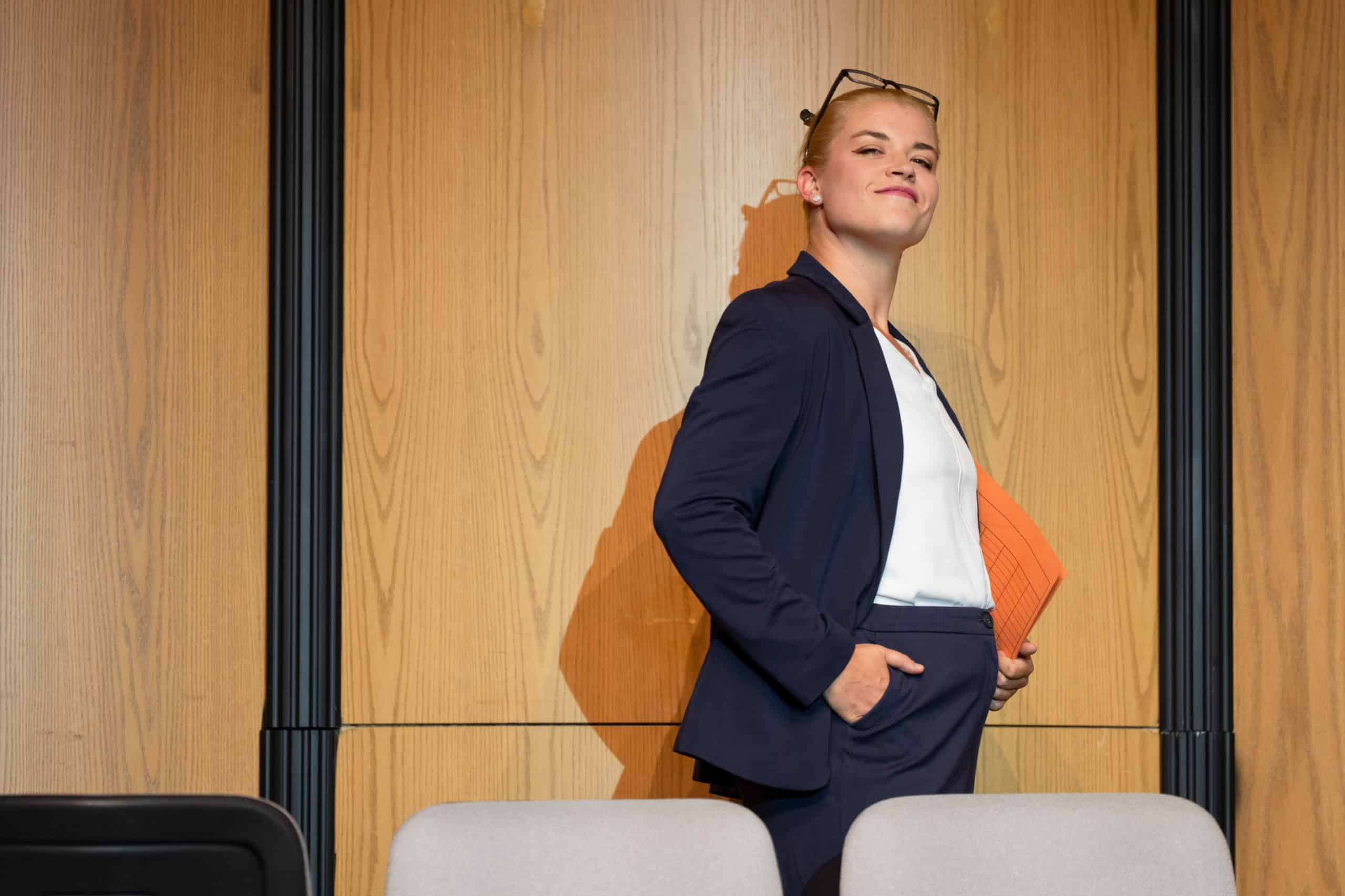 Szene aus Prima Facie zeigt eine selbstbewusste junge Anwältin in Anzug mit Aktenordner.